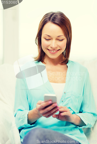 Image of smiling woman with smartphone at home
