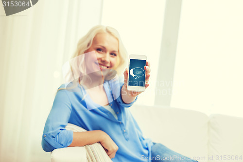 Image of smiling woman with smartphone at home