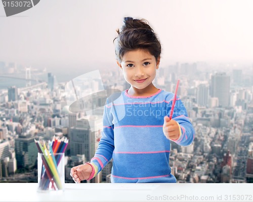 Image of happy little girl drawing with coloring pencils