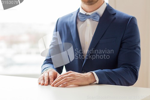 Image of close up of man in suit and bow-tie at table