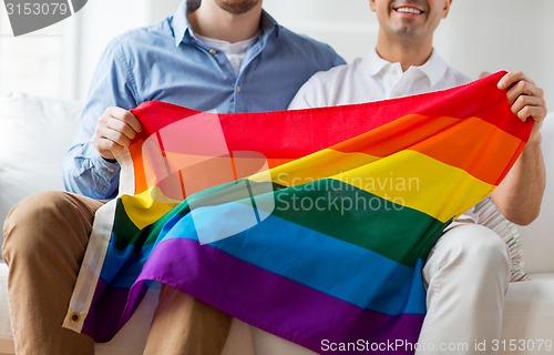 Image of close up of male gay couple holding rainbow flag