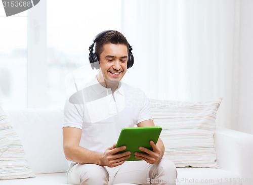 Image of smiling man with tablet pc and headphones at home