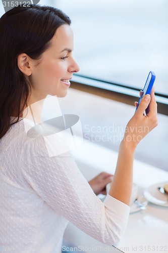 Image of smiling woman with smartphone and coffee at cafe