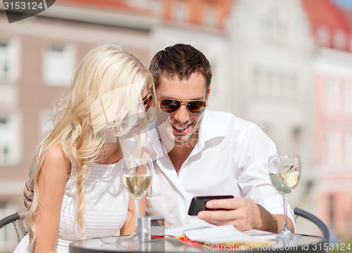 Image of couple looking at smartphone in cafe