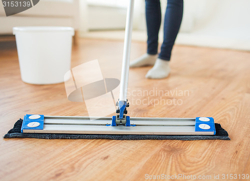 Image of close up of woman with mop cleaning floor at home