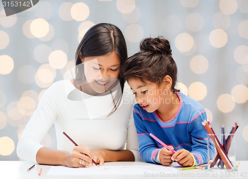 Image of happy mother and daughter drawing with pencils