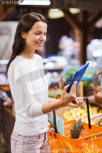 Image of happy woman with basket and tablet pc in market