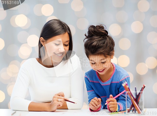 Image of happy mother and daughter drawing with pencils