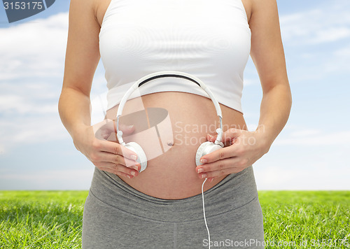 Image of close up of pregnant woman and headphones on tummy