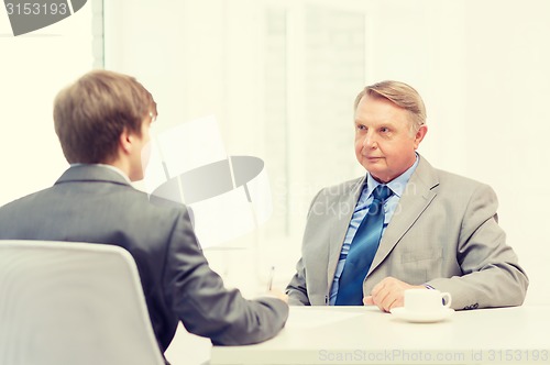 Image of older man and young man signing papers in office