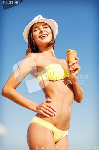Image of girl in bikini eating ice cream on the beach