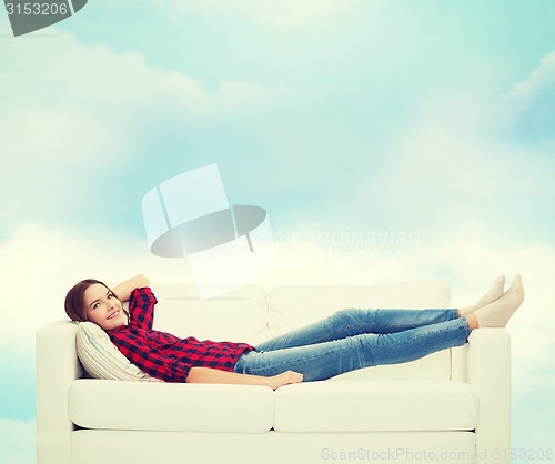 Image of smiling teenage girl lying on sofa
