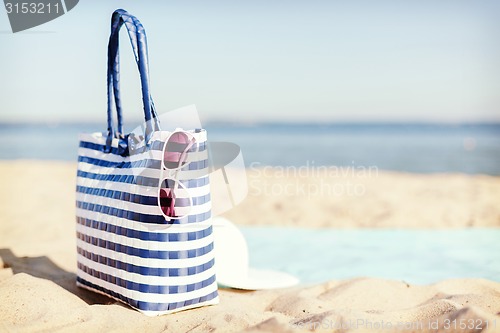 Image of straw hat, sunglasses and bag lying in the sand