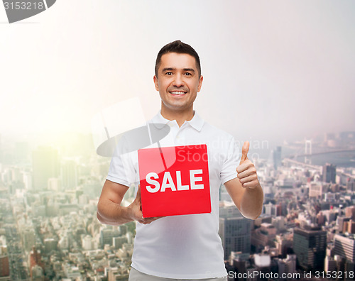 Image of smiling man with red sale sigh showing thumbs up