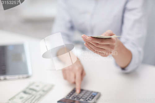 Image of close up of woman counting money with calculator