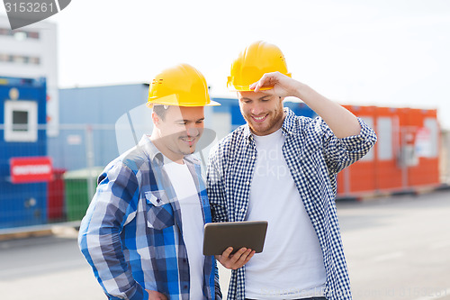 Image of smiling builders in hardhats with tablet pc