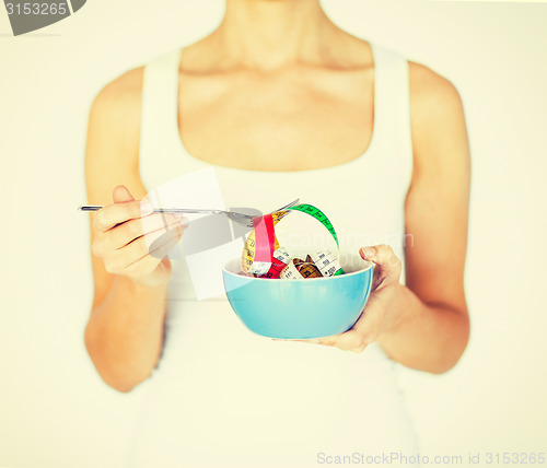 Image of woman hands holding bowl with measuring tape