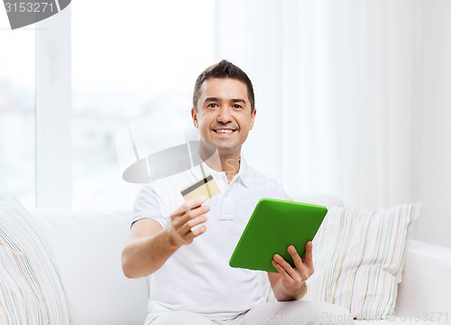 Image of smiling man working with tablet pc at home