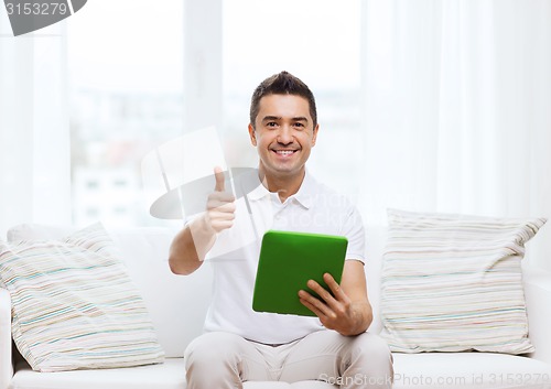 Image of smiling man working with tablet pc at home