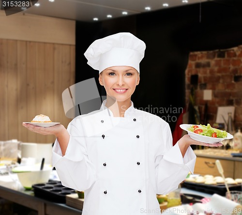 Image of smiling female chef with salad and cake on plates