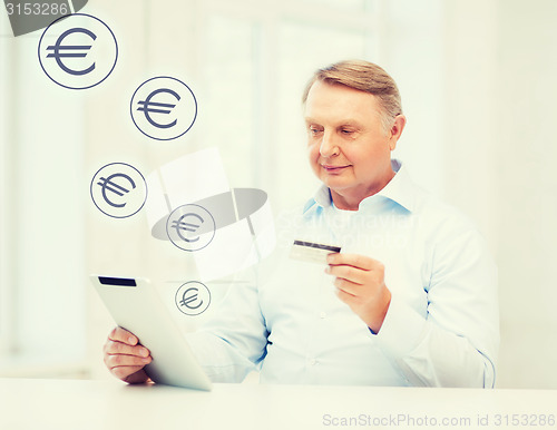 Image of old man with tablet pc and credit card at home