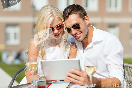 Image of couple looking at tablet pc in cafe