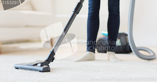 Image of close up of woman legs with vacuum cleaner at home