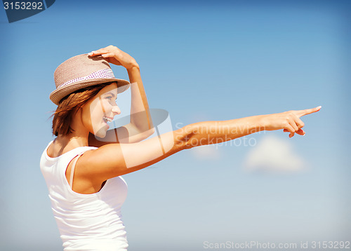 Image of girl in hat showing direction on the beach