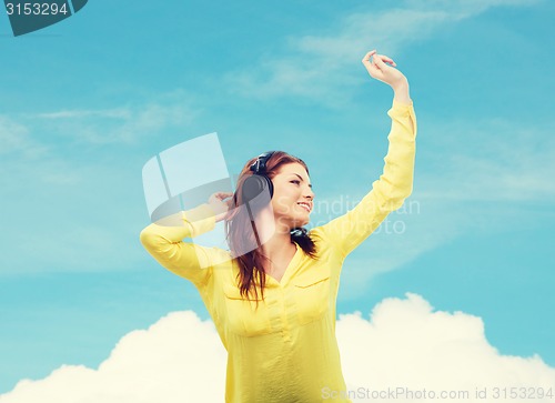 Image of teenage girl sitting on sofa with headphones