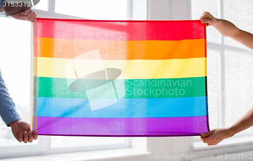 Image of close up of male gay couple holding rainbow flag