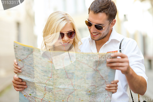 Image of smiling couple in sunglasses with map in the city