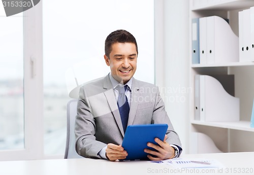 Image of smiling businessman with tablet pc in office