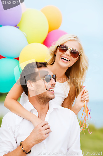 Image of couple with colorful balloons at seaside