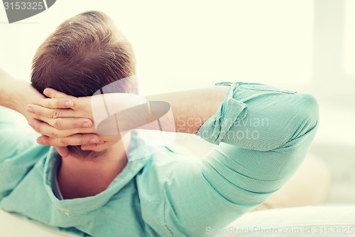 Image of man lying or sitting on sofa at home from back