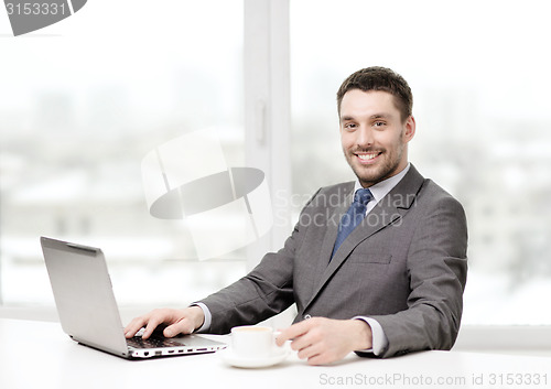 Image of smiling businessman with laptop and coffee