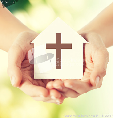 Image of close up of hands and paper house with cross