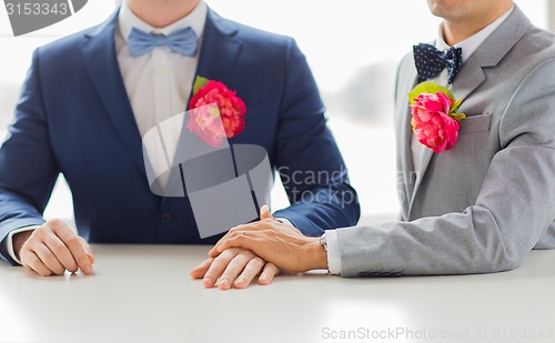 Image of close up of happy male gay couple holding hands