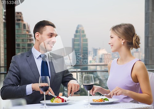 Image of smiling couple eating and talking at restaurant