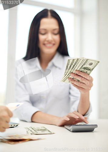 Image of close up of woman counting money with calculator