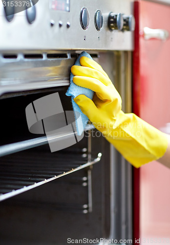 Image of close up of woman cleaning oven at home kitchen