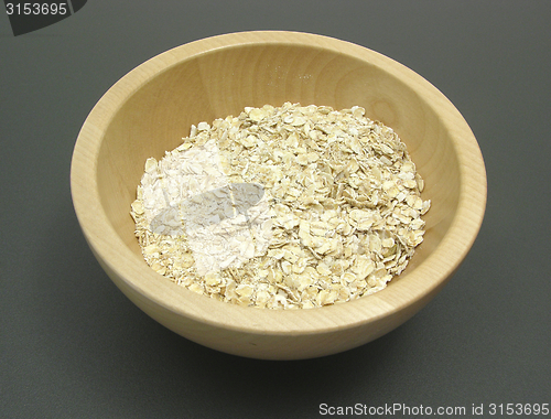 Image of Wooden bowl with oat flakes on a dull matting