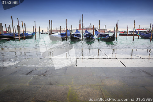 Image of Gondolas moored in front of pavement