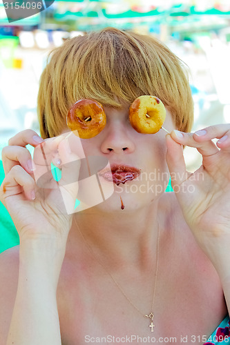 Image of Playful girl holding donuts on her eyes. 