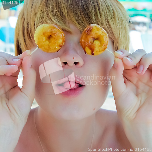 Image of Playful girl holding donuts on her eyes. 