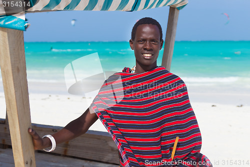 Image of Traditonaly dressed black man on beach. 