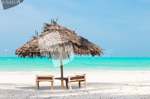 Image of Two deck chairs and umbrella on tropical beach.