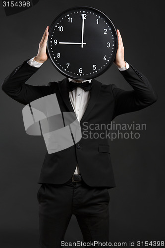 Image of Handsome young man holding a clock