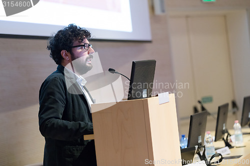 Image of Speaker giving talk on podium at Business Conference.