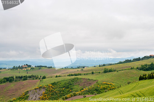 Image of Green hill under sky filled with clouds in Tuscany