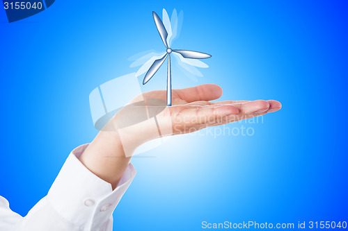 Image of Wind Turbine Turning In A Palm On Blue Background